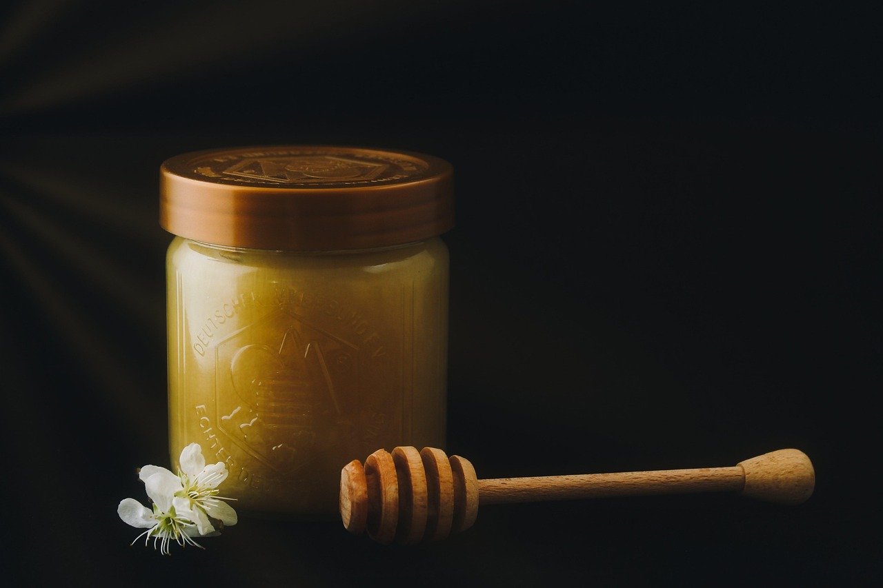 Close-up of honey being tasted from a wooden spoon, showing its golden color and texture.